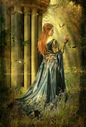 Goddess Cliodhna is standing in front of a pillared building. She is holding an apple while three birds surround her in a lavender field. Her red her hangs down her back while she is wearing a dark blue Celtic dress.